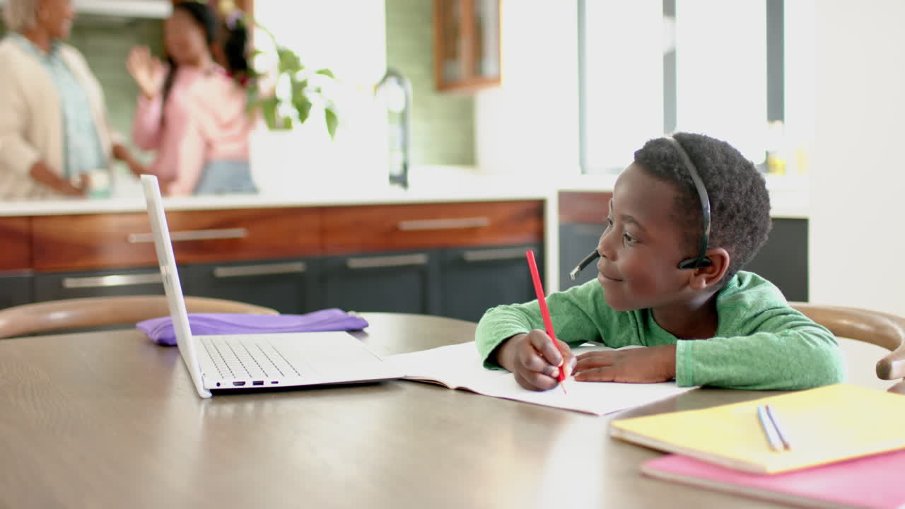 African american boy having online class using headphones and laptop with copy space, slow motion