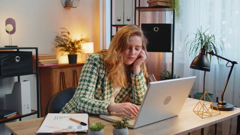 bored sleepy business woman worker working on laptop computer yawns leaning on hand at office desk