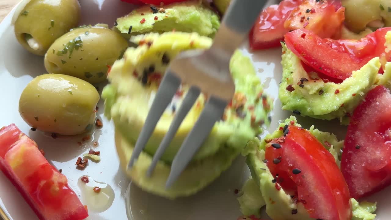 Close up of eating a healthy avocado salad with olives and olive oil and spices pov