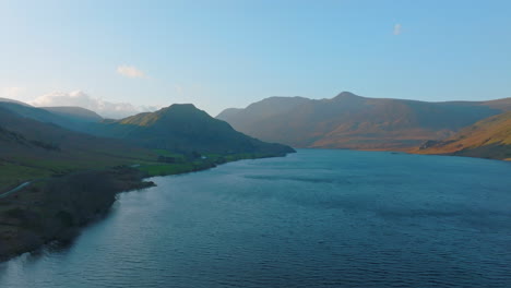 crummock water lake district unesco national park, aerial sunrise push forward over lake with sun dappled mountains