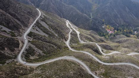 Vista-Aérea:-Los-Vehículos-Ascienden-Por-Caminos-De-Grava-En-Zigzag-Por-La-Ladera-De-La-Montaña