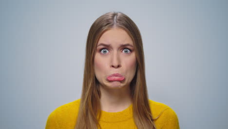 Portrait-of-beautiful-girl-making-grimaces-at-camera-on-grey-background.