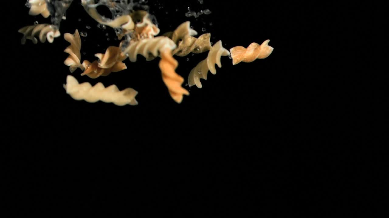 Animazione di pasta che cade nell'acqua su sfondo nero