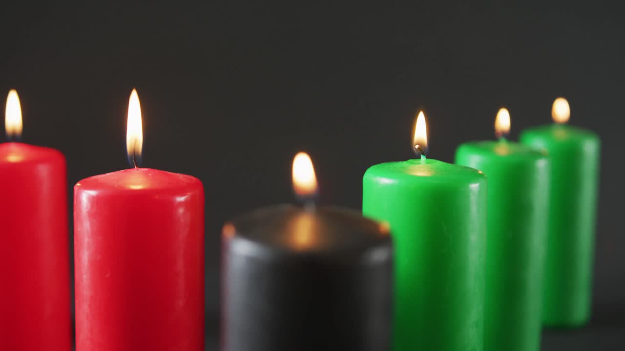 composición de velas verdes, negras y rojas encendidas de halloween contra un fondo negro