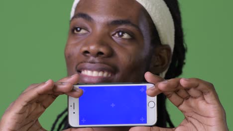 young handsome african man with dreadlocks against green background