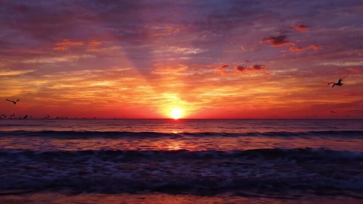 A Breathtaking Sunset Over the Ocean, Showcasing Vibrant Colors and Tranquil Waves as the Sun Sets Beyond the Horizon in a Spectacular Display of Nature's Beauty