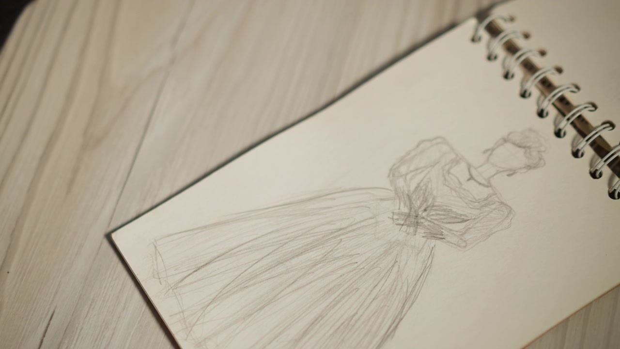 Schizzo artistico di un abito in un ambiente da studio. Primo piano di uno schizzo di abito che mostra sfumature e legatura. Gli ambienti di lavoro creativo sono immortalati con un'illustrazione dettagliata dell'abito e texture sfumate.
