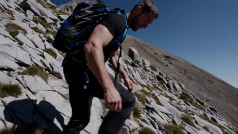 man hiking up a rocky mountain slope on a clear day