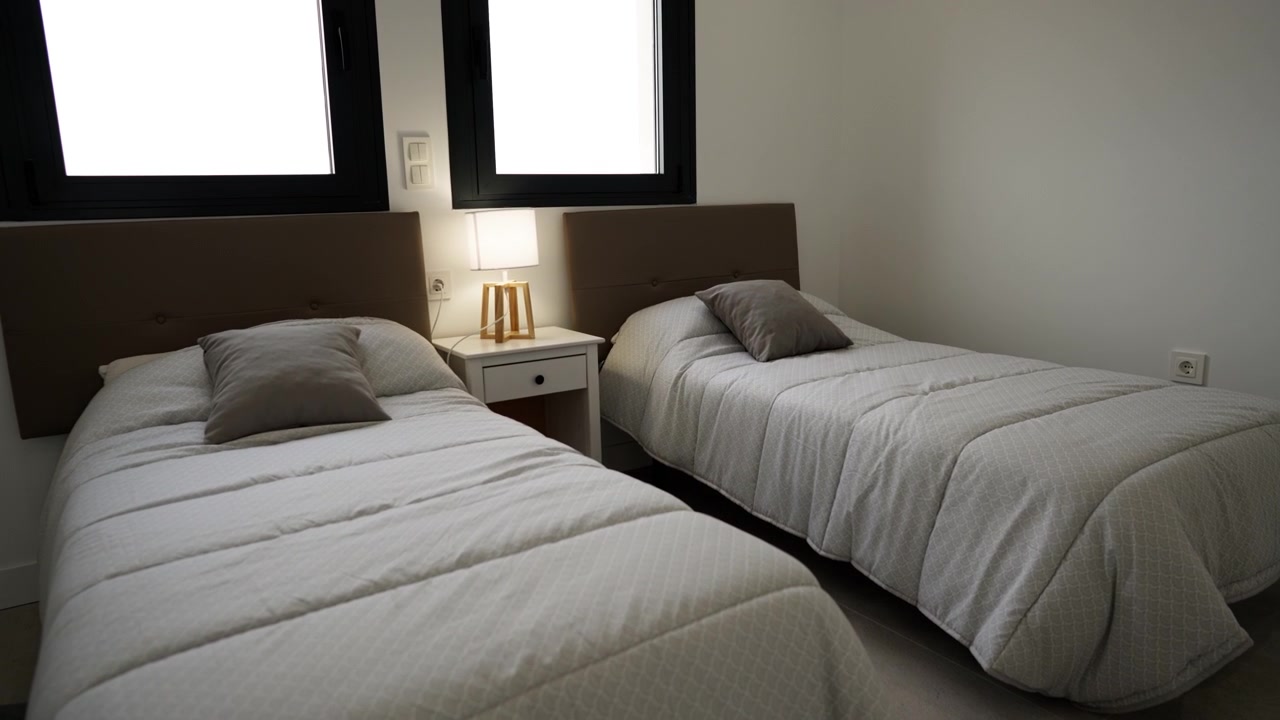 Modern twin bedroom with two single beds, bedside table and soft lighting. Clean minimal interior ideal for hotel, rental, or residential real estate concepts.