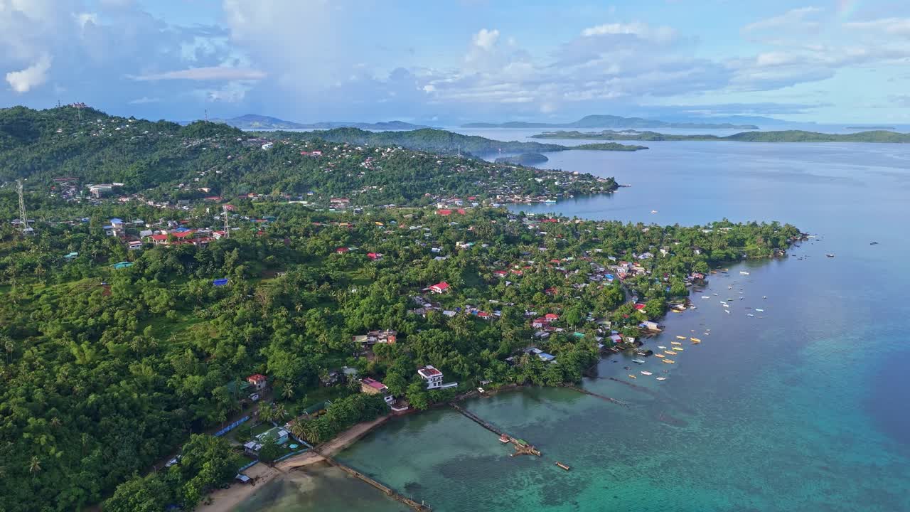 High-angle bird’s eye view of San Jose, the capital town of Dinagat Island, Philippines showing the coastal settlement, shoreline, surrounded by lush tropical scenery and ocean views.