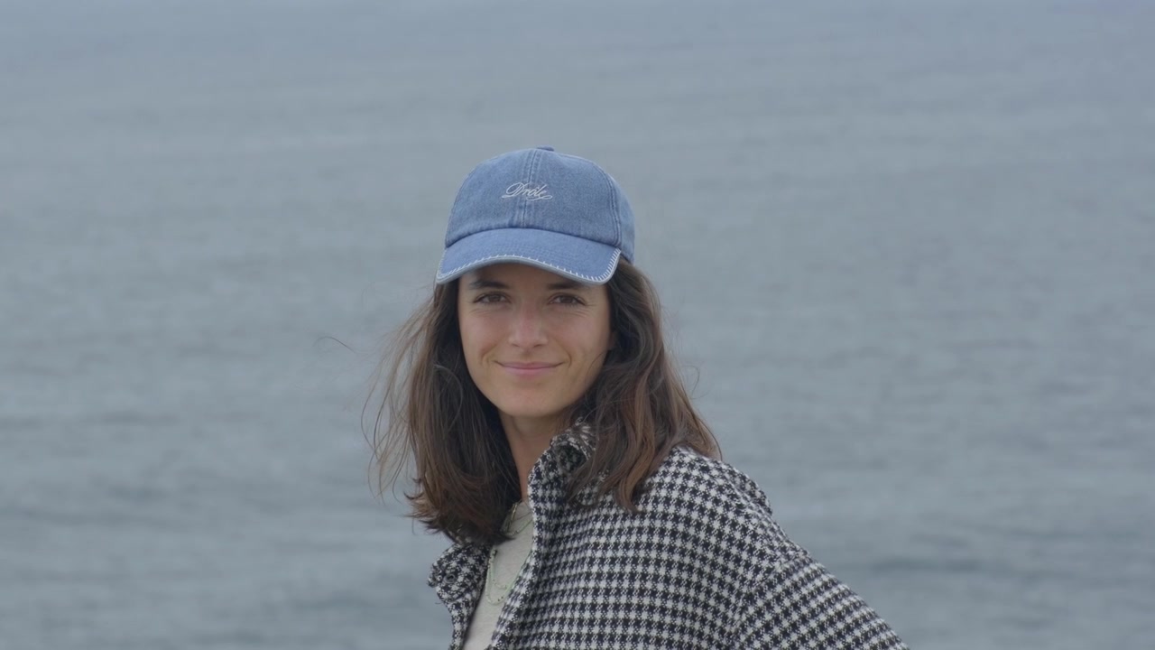 Slowmotion af smilende kvinde ved havet med vind i håret.