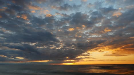 Time-lapse-sunset-over-the-sea,-sky-with-dark-clouds