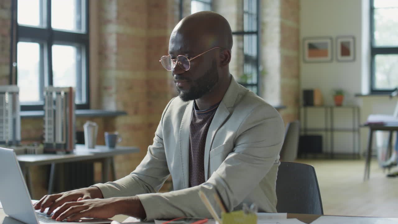 African American Man Working on Laptop in a Modern Office