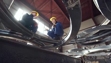 workers discussing metal parts at fabrication facility