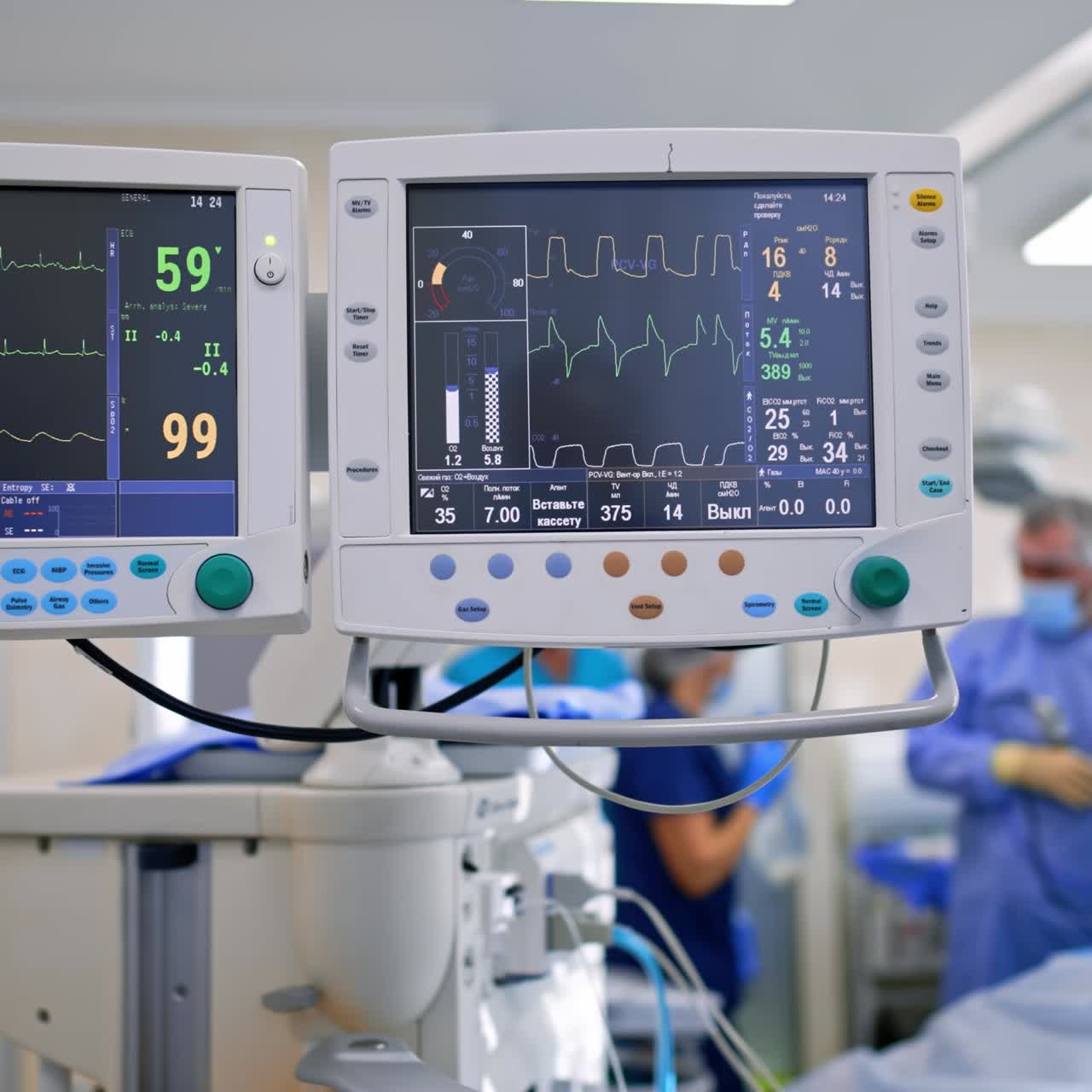 Two monitors of lung ventilator with patient's life signs. Medical team working at backdrop in blur