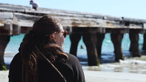 Nahaufnahme-Einer-Frau-Am-Strand,-Die-An-Einem-Windigen-Tag-In-Australien-Eine-Schwarze-Jacke-Trägt