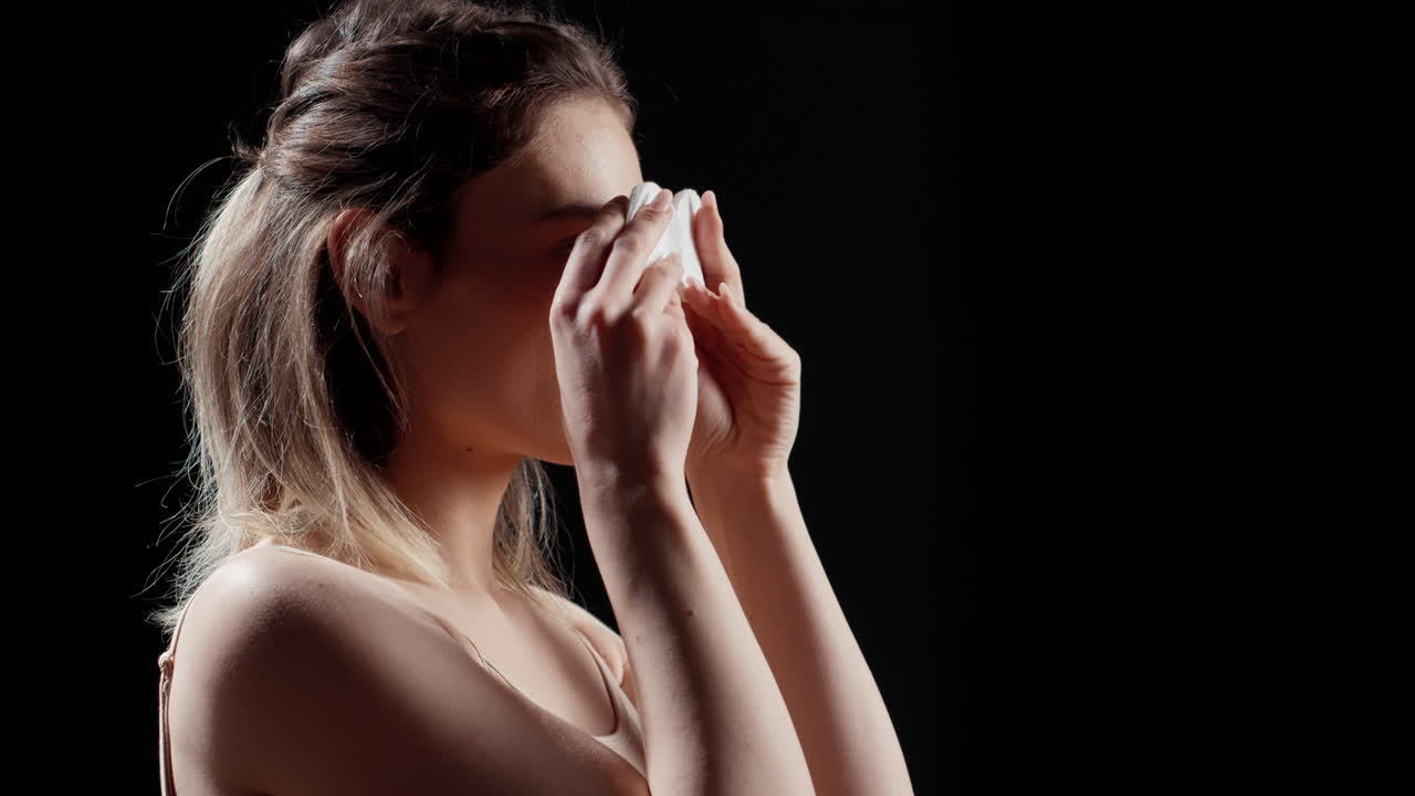 mujer quitando el maquillaje con almohadillas de algodón