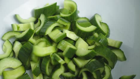 adding cucumber into deep white bowl