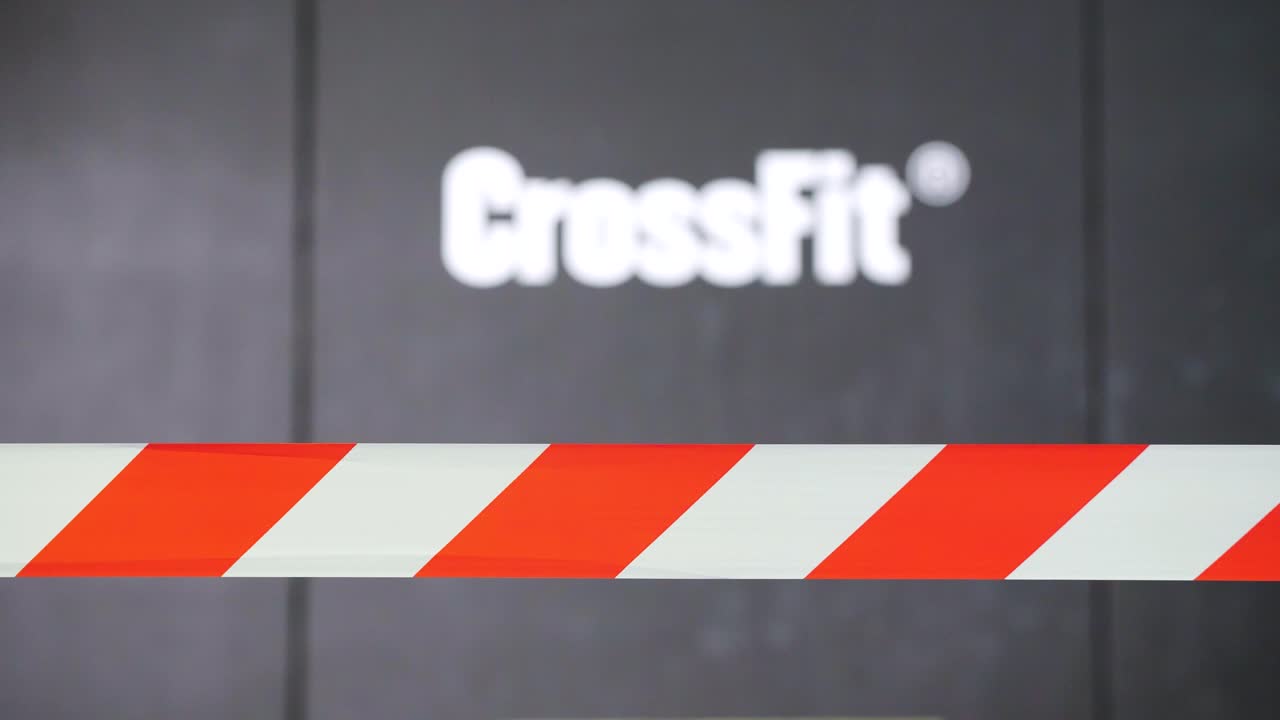 On the black wall, the word &amp;quot;Crossfit&amp;quot; is written in bold white letters, while in front of it, there is a white and orange tape, adding a vibrant touch to the surroundings
