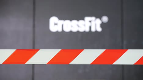 on the black wall, the word "crossfit" is written in bold white letters, while in front of it, there is a white and orange tape, adding a vibrant touch to the surroundings