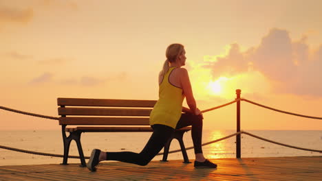 a young athlete makes a morning warm-up on the sea pier of a cool morning against the background of