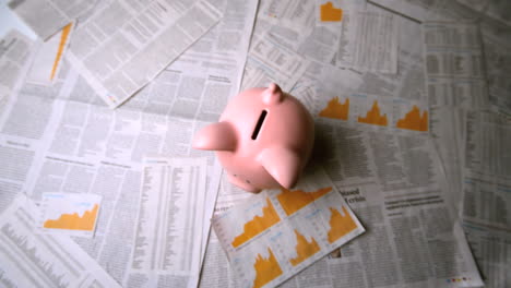 pink piggy bank falling over sheets of paper