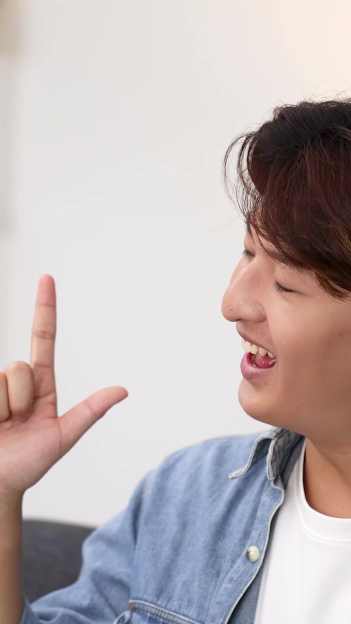 笑顔で笑いながらLサインを作る若い男性