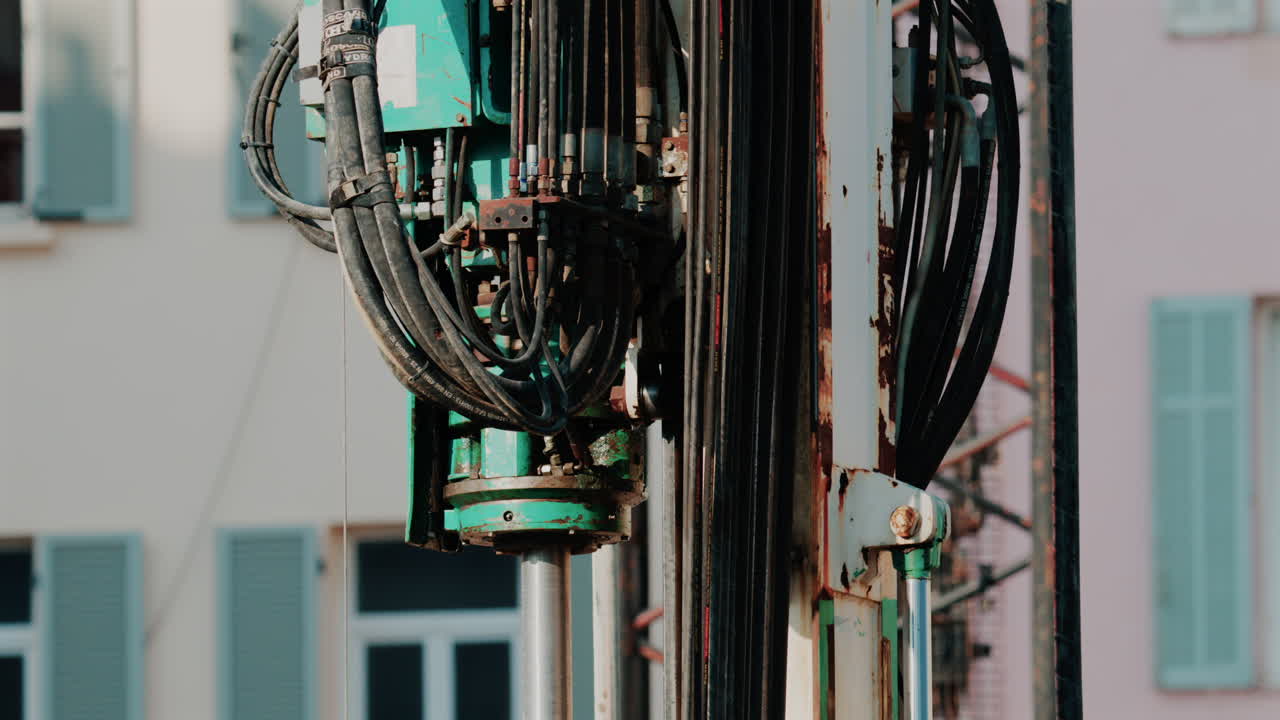 Close up of mechanical parts and hydraulic hoses of a construction drill