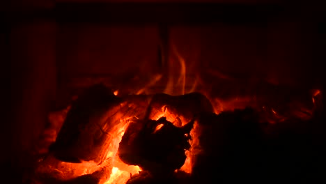 full screen view of fire in a wood stove with sparks in slow motion