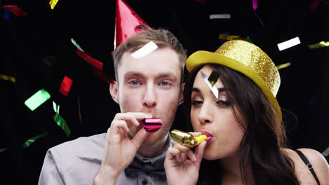pareja de raza mixta soplando cámara lenta en la cabina de fotos de la fiesta