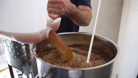 Hochauflösende-Aufnahme-Eines-Mannes,-Der-Flüssigkeit-In-Den-Fermenter-Gießt,-Um-Bier-Zu-Machen