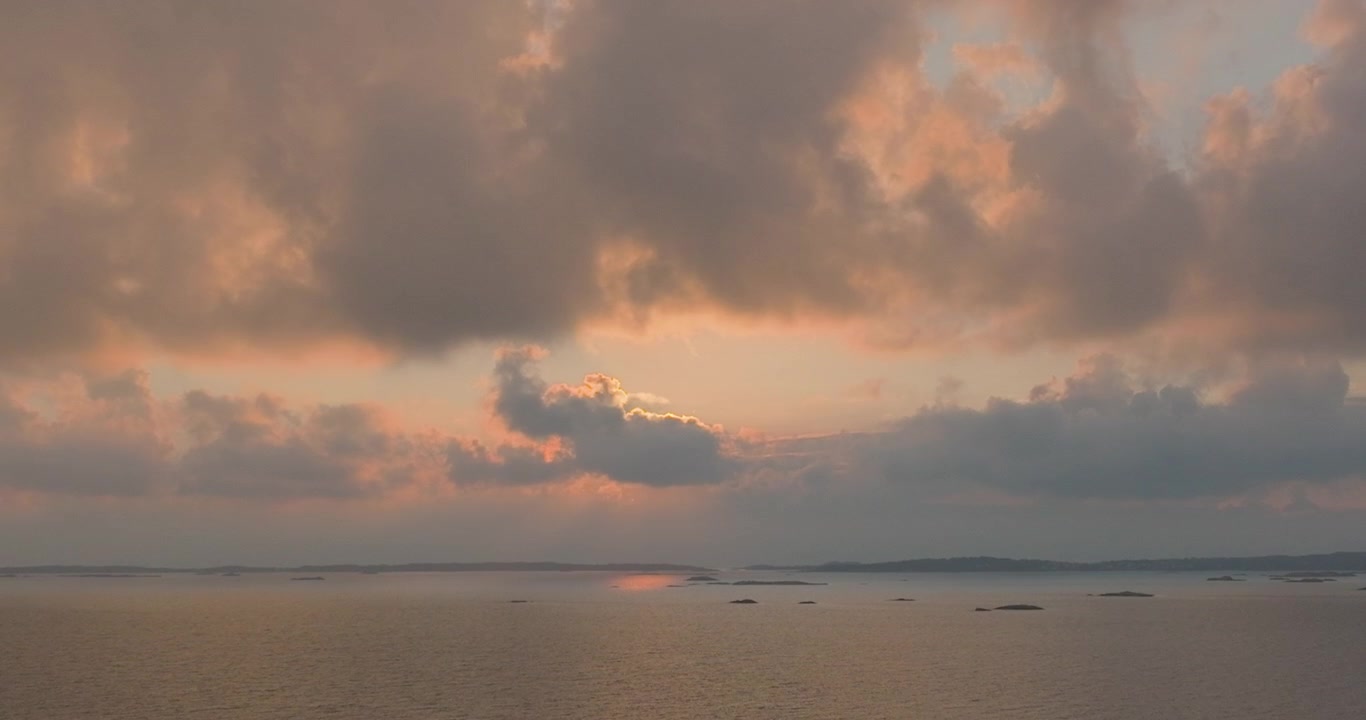 Drone clip over swedish ocean archipelago cliffs during sunset.