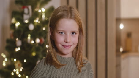 Vorderansicht-Eines-Blonden-Mädchens,-Das-In-Einem-Mit-Einem-Weihnachtsbaum-Geschmückten-Raum-In-Die-Kamera-Lächelt