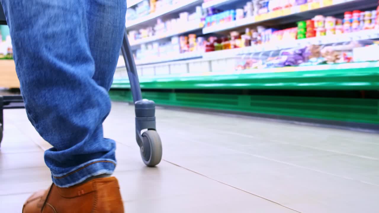 Grocery Shopping Journey: Captivating Footage of a Person's Steps While Pushing a Cart Through the Aisles of a Busy Supermarket, Highlighting Daily Life and Consumerism
