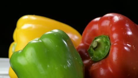 peppers yellow, red and green vegetables gyrating on black background