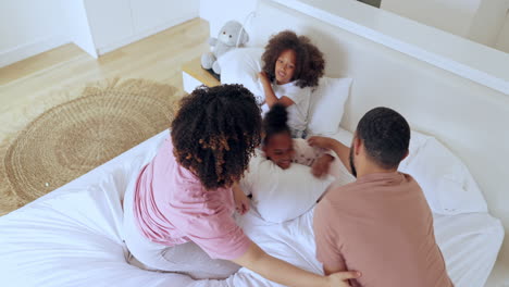 parents, children and pillow fight in bed