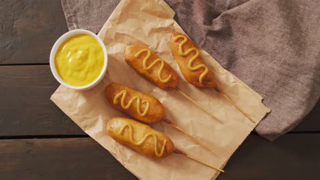 video of corn dogs with dip on a wooden surface