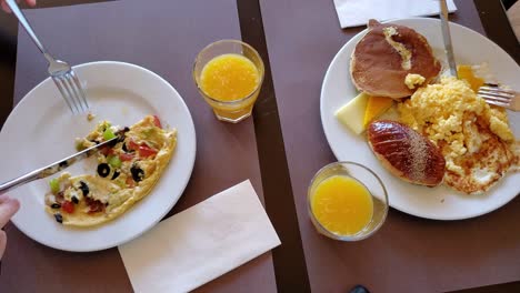 time lapse people eating with knives and forks from full plates and drinking orange juice