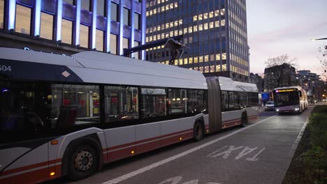 electric bus charging in the city at fall, vehicle behind is waiting to recharge -- public transport, wide shot