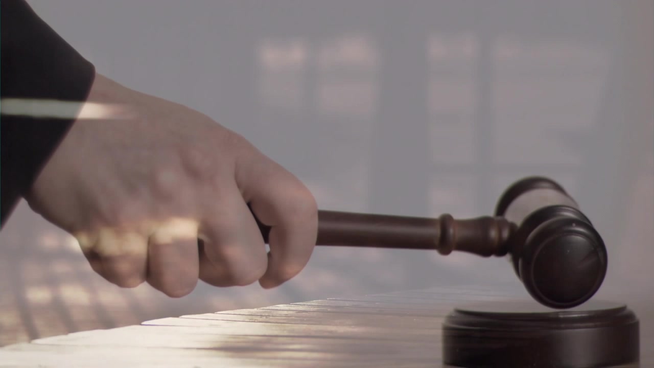 Mano derecha de un juez sujetando un mazo, golpeando el bloque de sonido, bajando el mazo, señalando una orden judicial