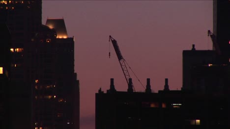 Una-Grúa-De-Construcción-Descansa-Sobre-Una-Azotea-En-Un-Horizonte-De-Hora-Dorada