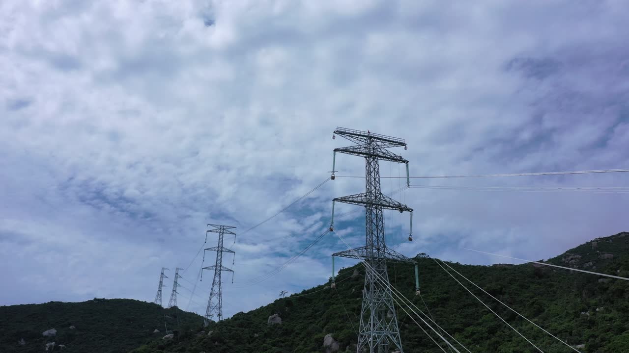 Aerial drone footage of high voltage power transmission towers with line pylon in mountainous area to distribute electricity - Natural landscape and industrial concept for sustainable development