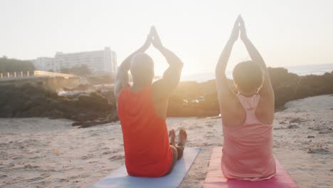 Glückliches-älteres-Afroamerikanisches-Paar,-Das-Yoga-Macht,-Am-Strand-Meditiert,-Zeitlupe