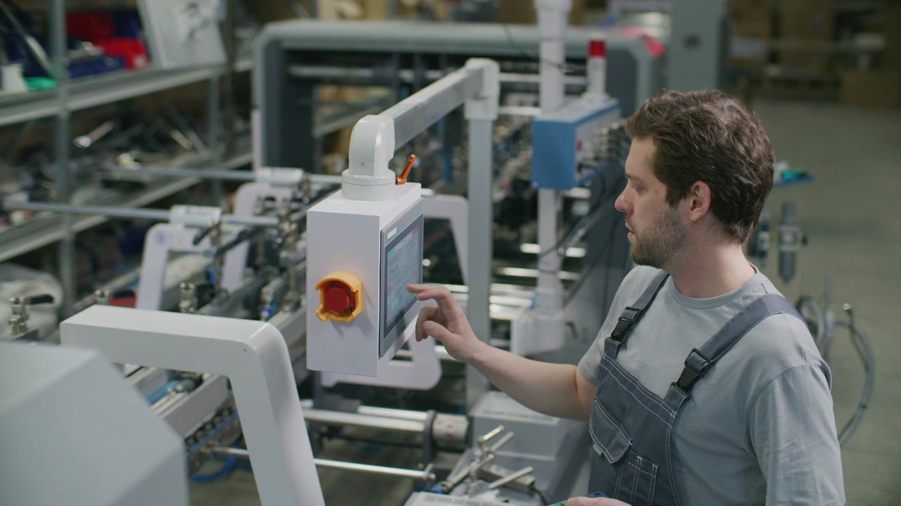 Industrial Worker Using Control Panel and Handheld Remote in Printing Factory