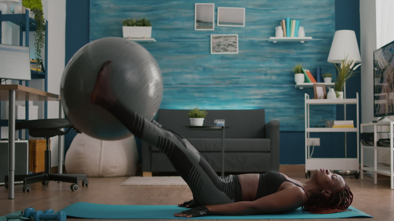 mujer negra delgada y en forma bombea la prensa muscular abdominal acostada en el suelo