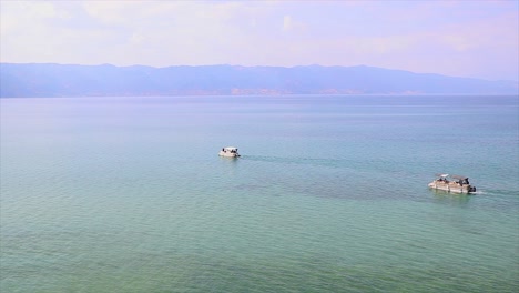 Two-ships-floating-on-a-water-of-a-natural-lake-one-after-another