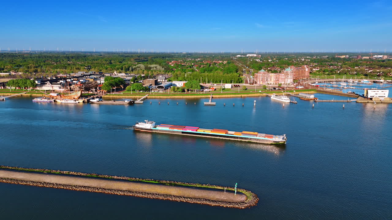 Loaded barge slowly moves by the waterscape of the Markemeer lake. Aerial perspective on the panorama of Lelystad, the Netherlands on beautiful sunny day.