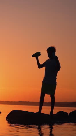 the boy throws a paper airplane. beautiful sunset. origami. vertical video