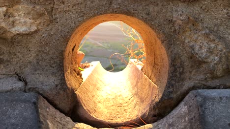 Hermosa-Vista-Del-Atardecer-En-La-Hora-Dorada-En-Ronda-A-Través-De-Un-Agujero-En-Una-Pared,-Vista-De-La-Naturaleza-Y-Los-Campos-En-España,-Perspectiva-Interesante,-Esperanza-Al-Final-Del-Túnel,-Toma-De-4k