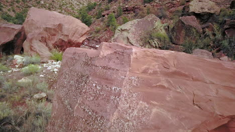 Langsamer-Flug-über-Felsbrocken-Und-Rote-Felsen-In-Der-Schlucht